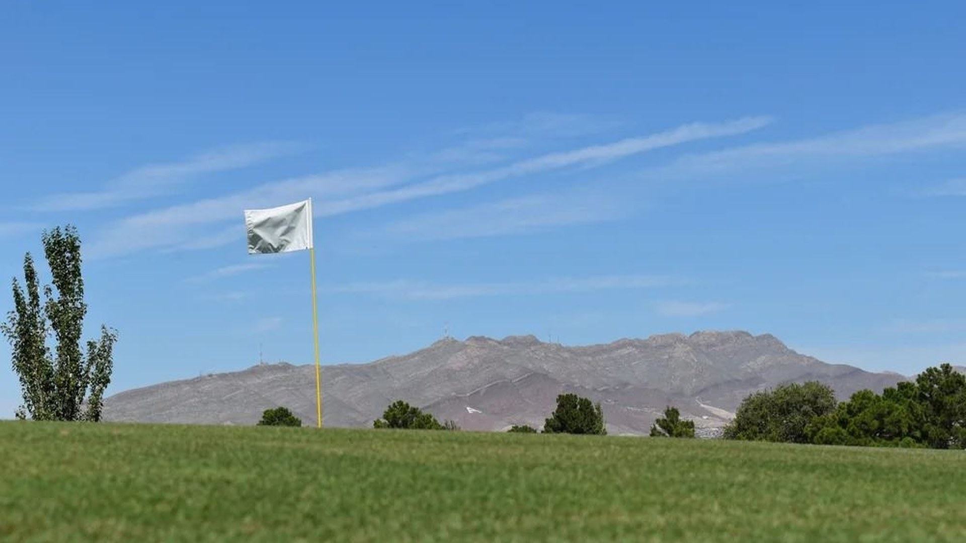 Flag on a green at Ascarate Golf Course with El Paso mountains in the background.
