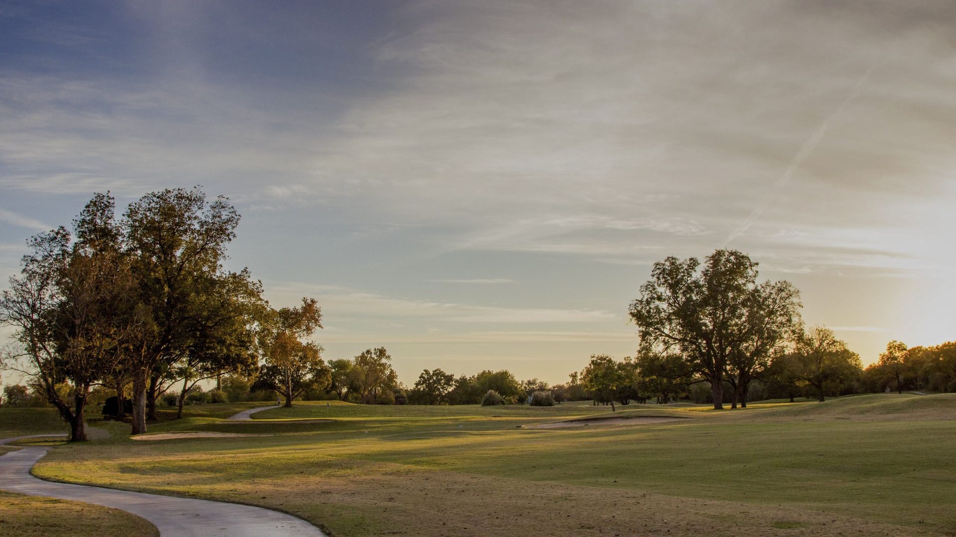 Tree-lined fairway, green, and sand bunker at Riverside Golf Course in Austin.