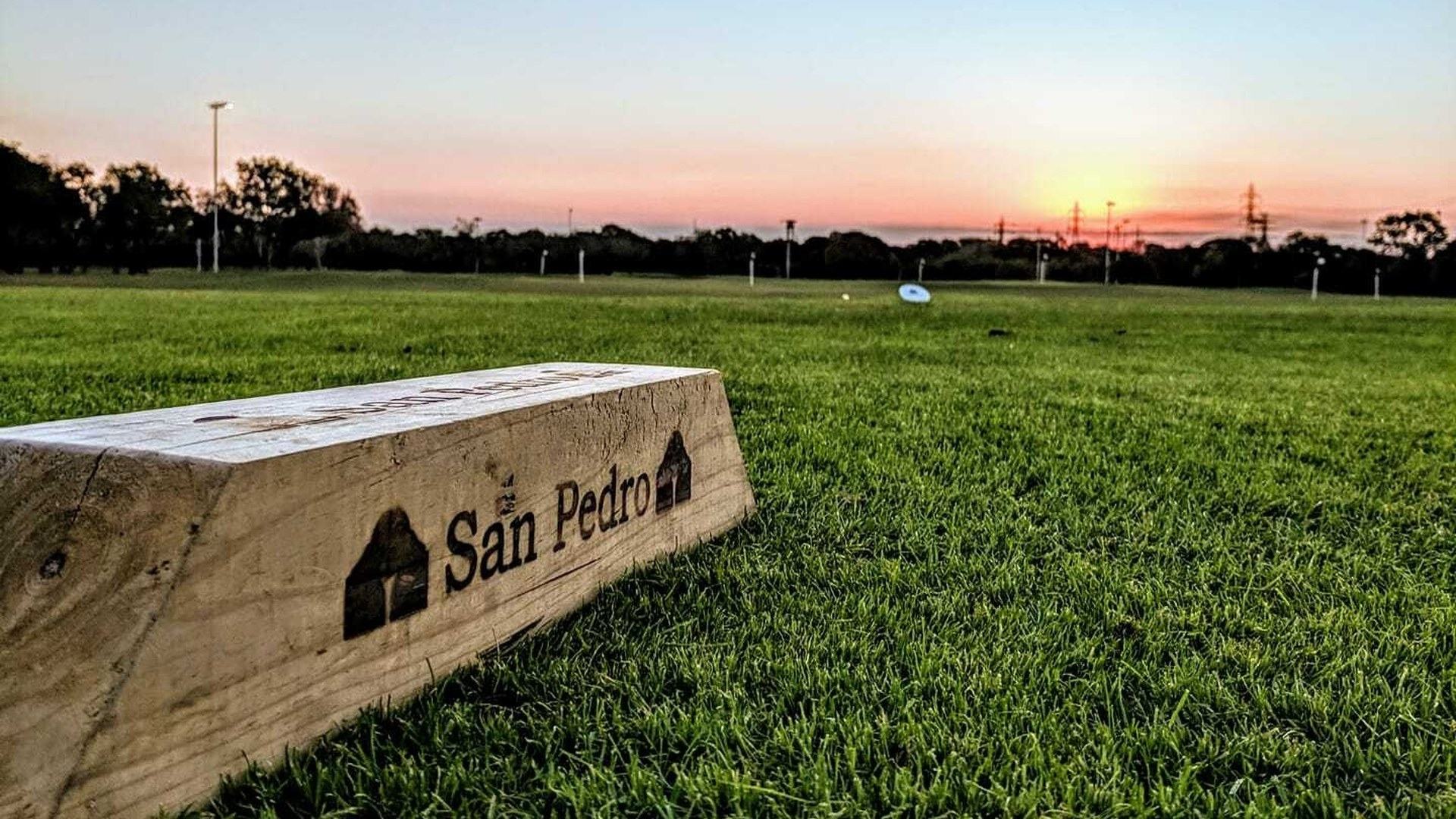 San Pedro tee marker beside a golf green at sunset in San Antonio.