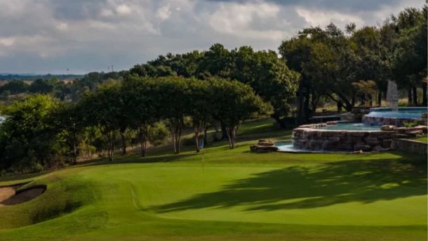Green beside a tiered stone fountain and mature trees at Avery Ranch Golf Club in Austin.
