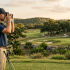 Golfer using binoculars beside his clubs on a scenic golf course